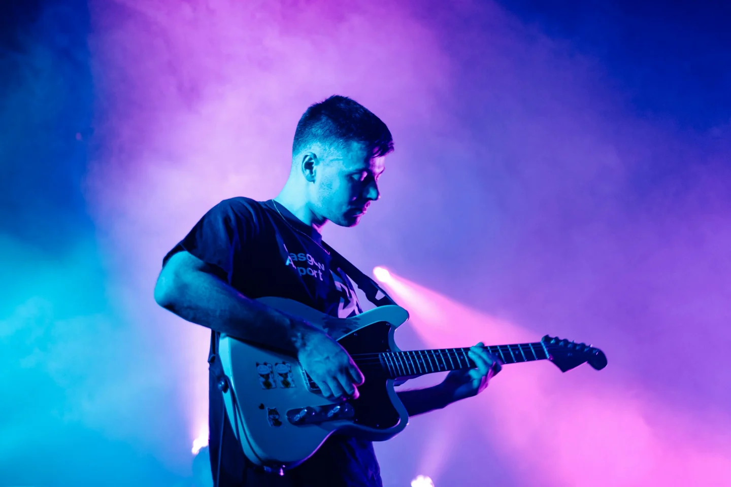 Chanteur et musicien du groupe "La troupe du soleil levant" sur scène, avec fond coloré